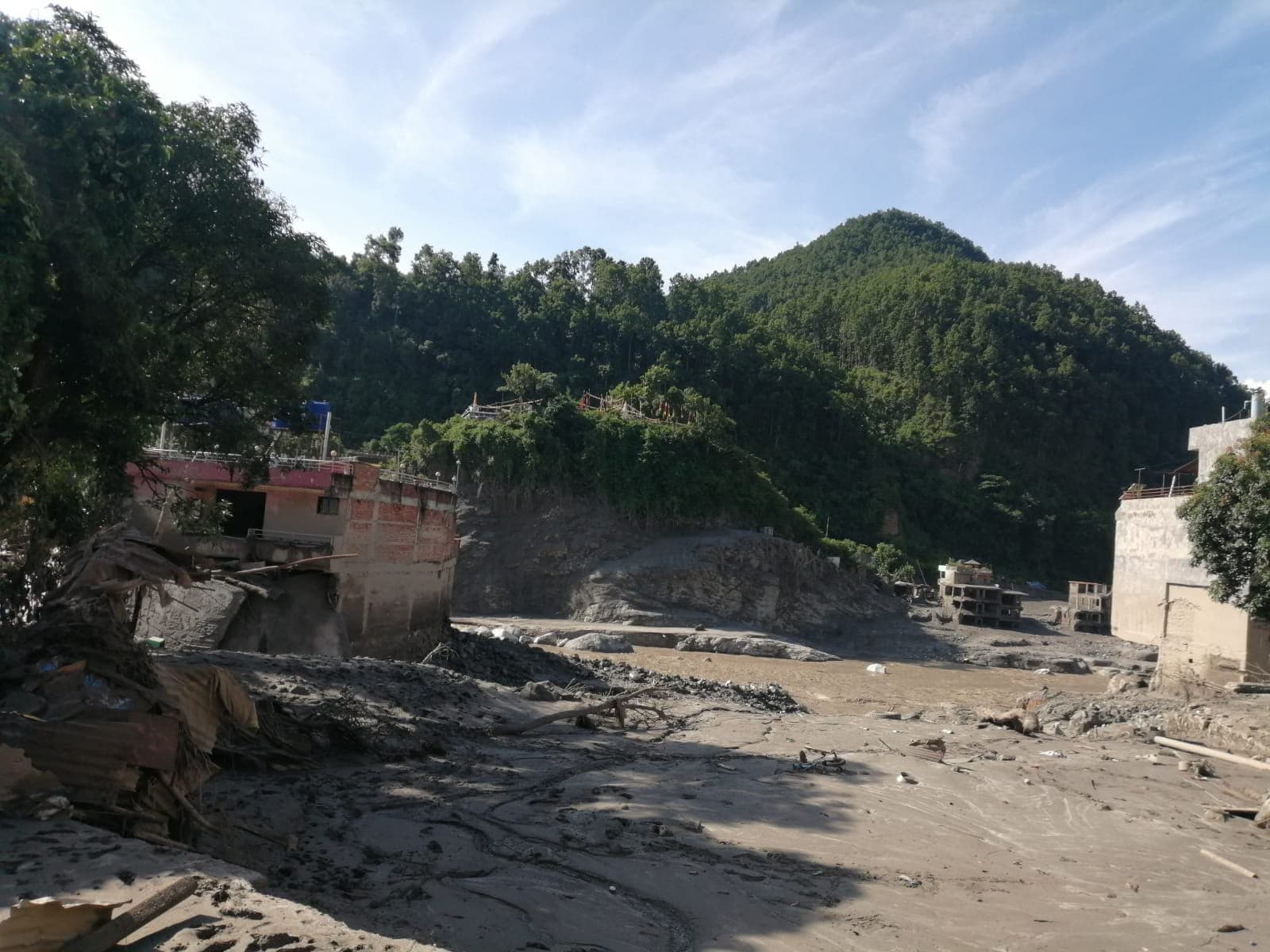 Riverbank erosion and damaged housing on gravel plain